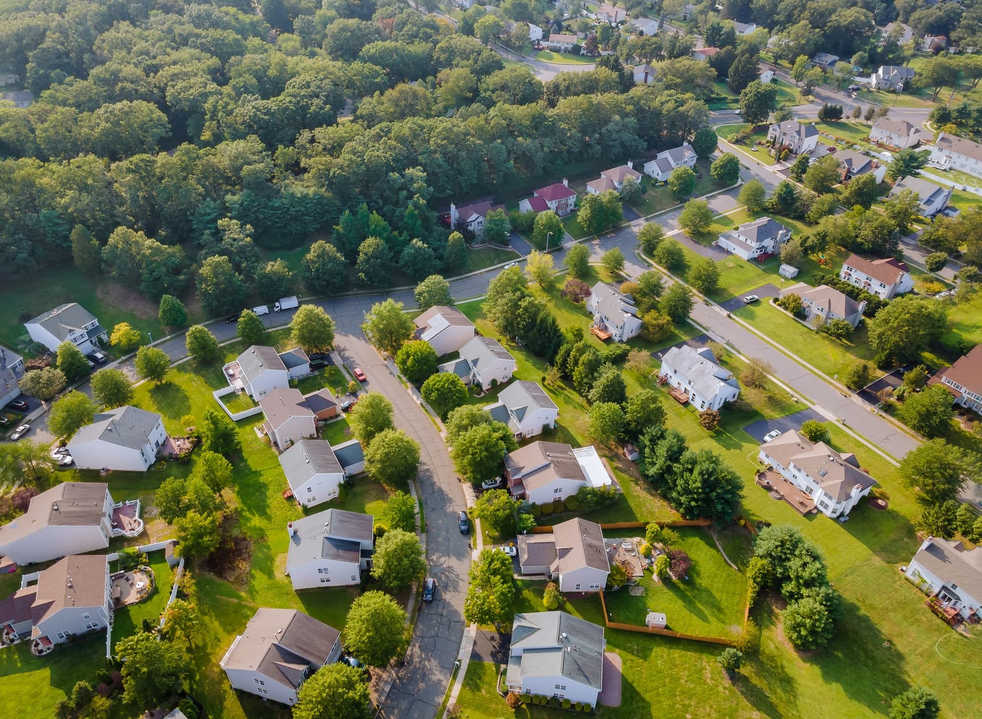 Aerial view of a suburban neighborhood of detached houses set among wooded hills